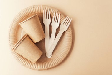 Biyo-çözünebilir kağıt bardaklar ve tahta çatallar, krem surfac 'a yakın kese kağıdına yerleştirilmiş.