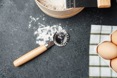 Un, yumurta ve mutfak aletleri koyu bir tezgahta pişirmek için düzenlenir..