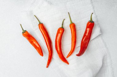 Parlak kırmızı biberler düzgün bir düzende beyaz bir kumaşın üzerine serilir..