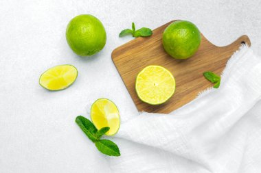 Parlak yeşil limonlar, ferahlığı arttıran nane yapraklarıyla ahşap bir tahtada dilimlenir..