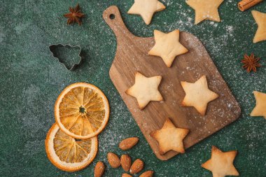 Noel yıldızı kurabiye hamuru ve portakallar şenlikli pişirme ve mevsimlik konsept için yeşil arka planda