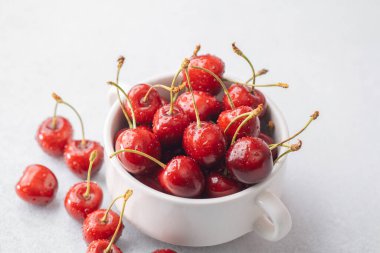 Kirazlar beyaz kaseye saçılmış. Atıştırmalık hazırlığı ya da parlak yemek tasarımı için.