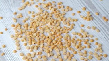 Kuru sarı bezelyeler, parlak desenli ahşap bir yüzeye rastgele dağılmış, pişirilmeye hazır..