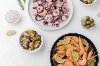 Karides ahtapot midyeli deniz ürünleri tabağı ve yemek servisi için beyaz masada zeytin.