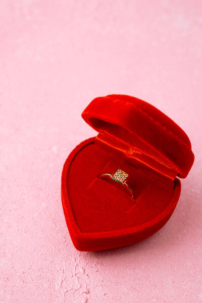 Квадратное кольцо с бриллиантом в красной коробке сердца на розовом фоне