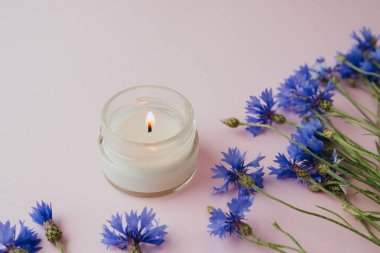 Pembe arka planda mum ve çiçek