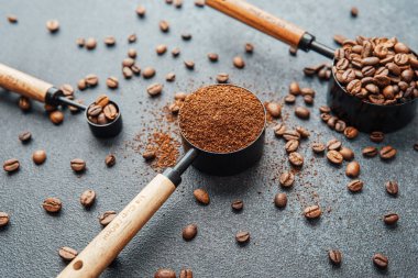 Koyu arka plandaki kepçeleri ölçmek için öğütülmüş kahve ve fasulye.