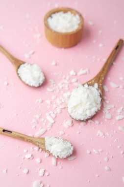 Pastel pembe arka planda soya mumu tanecikli çoklu tahta kaşıklar.