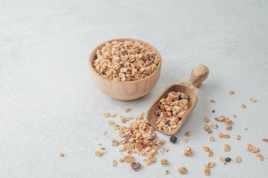 Tahta kasede granola ve açık gri arka planda kepçe