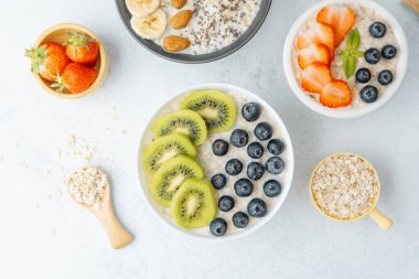 Beyaz yüzeyde meyve ve tahıllı yulaf ezmesi kaseleri.