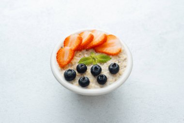 Beyaz arka planda yulaf ezmesi, çilek ve yaban mersini manzarası