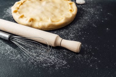 Hamur, çırpılmış çırpı ve oklavayla karanlık bir mutfak tezgahına yuvarlanır..