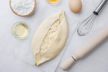 Beyaz zemin üzerinde yumurta sarısı ve peynirli çiğ khachapuri.