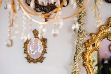 Eski bir ayna ve ışıltılı bir avize dekorun zarafetini arttırır..