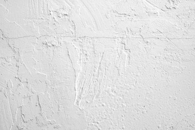 Çeşitli dokular ve küçük kusurlardan oluşan beyaz bir duvarın yakın çekimi..