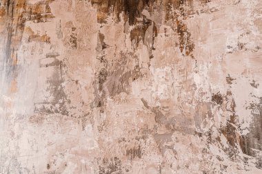 Dokulu bir duvar, sanatsal tasarım sergilenen, dünyevi tonlar ve soyut desenler içerir..