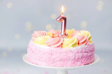 Bir numaralı mumun yer aldığı renkli pembe pasta bir doğum günü kutlaması için hazırlanıyor..