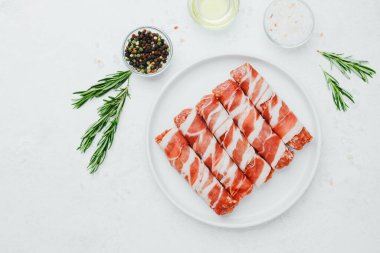 Jambona sarılmış sosis, beyaz tabakta otlar ve yağla birlikte.