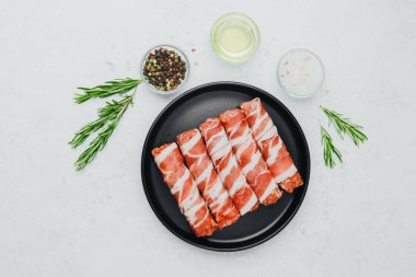 Domuz pastırması siyah tabakta baharat ve biberiye ile sarılmış.