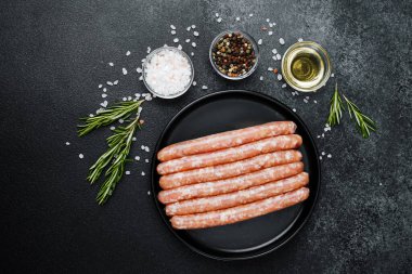 Siyah tabakta çiğ domuz sosisi ve biberiye.