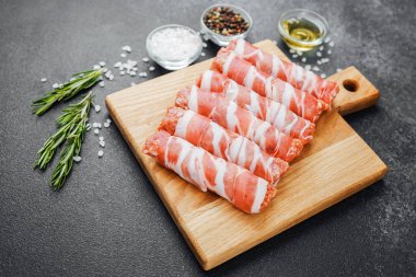 Pastırmaya sarılı çiğ et ruloları ahşap tahtaya baharatlı.