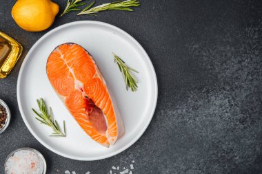 Canlı bir somon filetosu beyaz bir tabağa konur, otlar ve limonla..