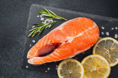 Somon bifteği dilimlenmiş limon ve taze biberiye filizlerinin yanında sergilenir..