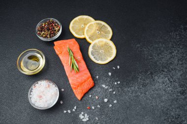 Taze somon filetosuna koyu arkaplanda limon dilimleri ve renkli baharatlar eşlik eder..