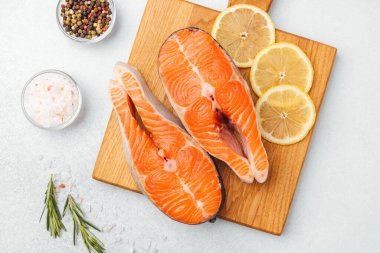 Limon dilimleri ve baharatlarla hazırlanmış parlak somon filetoları pişirmeye hazır..