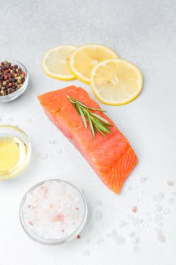 Bitkilerle süslenmiş lezzetli somon filetosu ve yanında limon dilimleri ve baharatlar..