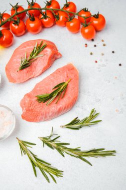 Beyaz arka planda baharatlı dana bifteği ve bitkilerin üst görüntüsü, yakın plan yağ ve biber dahil.