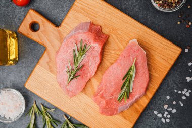 Biberiyeli dana bifteği, ahşap kesim tahtası ve yemek malzemesi.