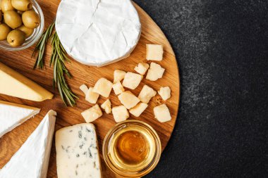 Tahta üzerinde zeytin, bal ve bitkilerle nefis peynir çeşitleri..