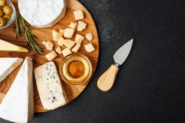 Zeytin ve ballı ahşap bir tahtanın üzerine dizilmiş çeşitli peynirler..