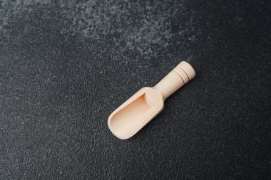 Küçük bir ahşap kepçe mutfaktaki dokulu karanlık bir yüzeye dayanır..