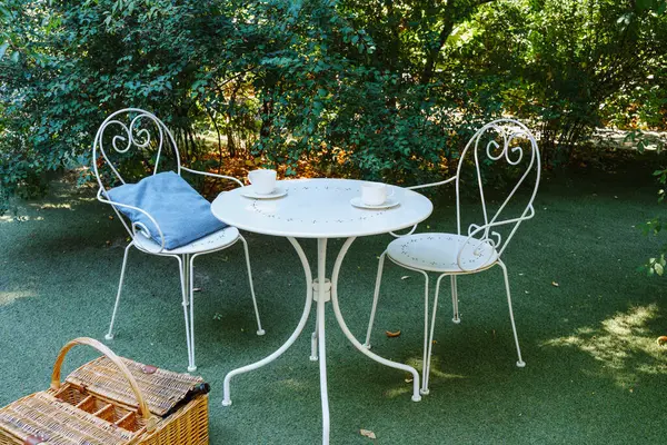 Bahçe çay seti beyaz demir mobilya ve piknik sepeti yaz rahatlama ve yaşam tarzı için 