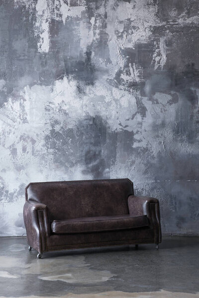 Brown vintage leather sofa in industrial interior for home decor and furniture catalog 