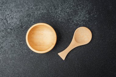 Yemek hazırlamak ve servis etmek için yapılmış eşleşen bir kaşığın yanında ahşap bir kase..