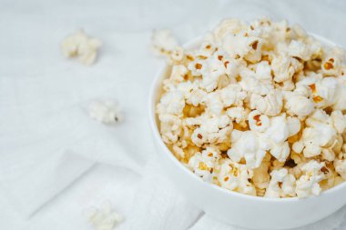 Beyaz bir kasede tereyağlı patlamış mısır. Evde sıcak bir film gecesi için hazır..