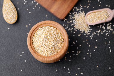 Çoklu tahta kaselerde kinoa tohumları ve karanlık arka planda kaşıklar.