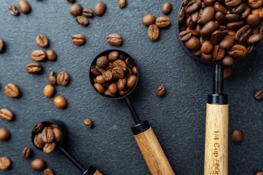 Koyu arkaplanda kaşık ölçmede kahve çekirdekleri