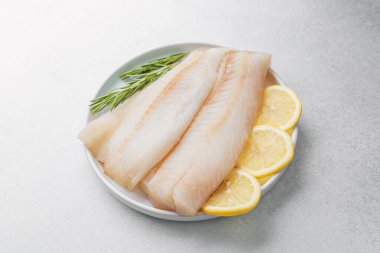 Beyaz arka planda limonlu ve biberiyeli ham pollock fileto.