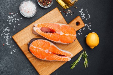 Parlak portakallı somon filetosu yanında baharat ve limon olan ahşap bir tahtanın üzerinde duruyordu..