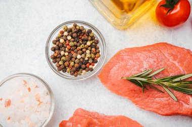 Yakın plan pembe Himalaya tuzu, biber ve beyaz arka planda biberiyeli çiğ biftek.