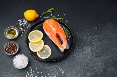 Somon filetosu, limon dilimleri ve pişirmeye hazır otlarla birlikte bir tabağa konur..