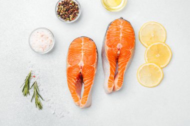 Limon dilimleri, baharatlar ve pişirmek için bitkilerle sergilenen taze somon filetoları..