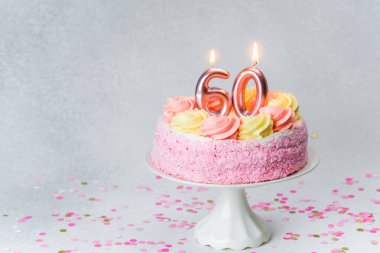 Mumlarla süslenmiş pembe ve sarı bir doğum günü pastası 60. özel kutlamadır..
