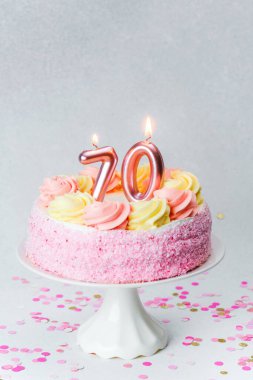 Kutlama atmosferinde mumlarla kaplı canlı pembe bir doğum günü pastası..