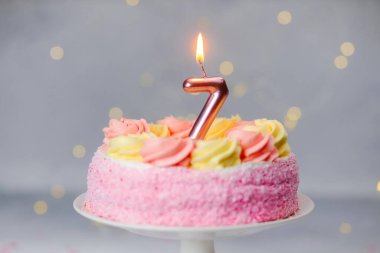 Parlak pembe ve sarı bir pasta bir kutlama için yedi numaralı parlak mumu içerir..