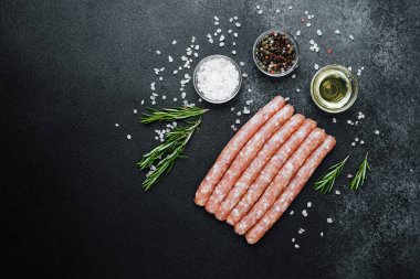 Siyah taş masada baharatlı çiğ sosisler.